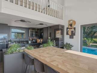 This stunning kitchen boasts a modern design with sleek, dark cabinetry and a spacious wooden island, perfect for both cooking and entertaining.