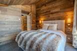 Experience rustic charm in this cozy bedroom featuring stunning wood paneling and a luxurious faux fur blanket.