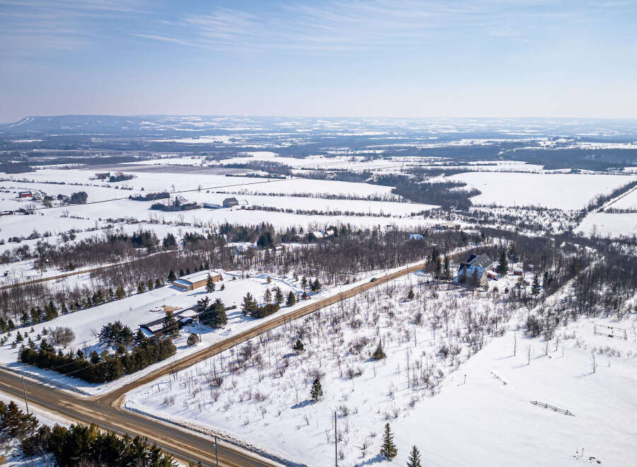 This stunning aerial view showcases a picturesque winter landscape, perfect for those seeking a serene rural retreat.