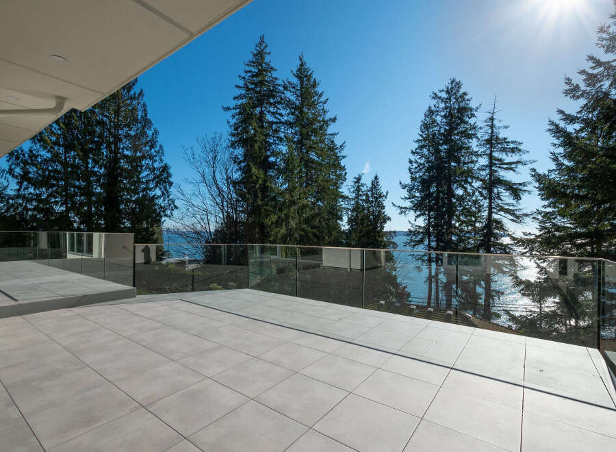 Enjoy breathtaking views from this stunning property! This modern home features a spacious outdoor patio with glass railings, perfect for entertaining or relaxing.