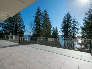 Enjoy breathtaking views from this stunning property! This modern home features a spacious outdoor patio with glass railings, perfect for entertaining or relaxing.