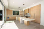 This stunning modern kitchen boasts sleek, light wood cabinetry and a spacious island with a marble countertop, perfect for both cooking and entertaining.