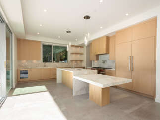 This stunning modern kitchen boasts sleek, light wood cabinetry and a spacious island with a marble countertop, perfect for both cooking and entertaining.