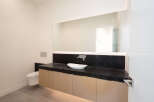 This modern bathroom features a sleek design with a black countertop and light wood cabinets.