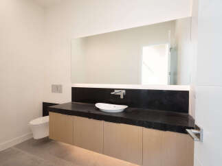 This modern bathroom features a sleek design with a black countertop and light wood cabinets.