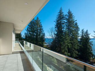 Enjoy breathtaking views from this stunning balcony overlooking the ocean and lush greenery.