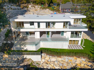 This stunning modern home offers luxurious living with its sleek design and expansive glass windows.
