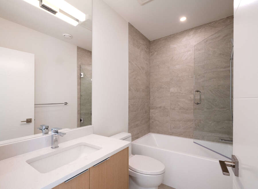 Step into this modern bathroom, featuring a sleek vanity with a pristine white countertop and a stylish faucet.
