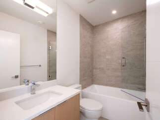 Step into this modern bathroom, featuring a sleek vanity with a pristine white countertop and a stylish faucet.