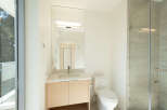 This modern bathroom boasts a sleek design with a large mirror, a stylish vanity, and a contemporary toilet.