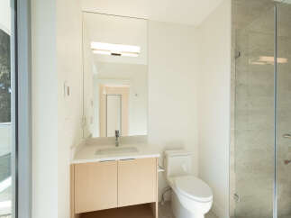 This modern bathroom boasts a sleek design with a large mirror, a stylish vanity, and a contemporary toilet.