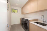 This modern laundry room features sleek cabinetry, a stainless steel sink, and a washer and dryer.