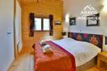 Discover the charm of this cozy bedroom, featuring a warm wooden interior and a comfortable bed.