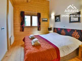Discover the charm of this cozy bedroom, featuring a warm wooden interior and a comfortable bed.