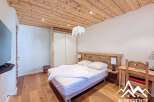 Discover a cozy bedroom retreat with a rustic wooden ceiling and flooring, creating a warm and inviting atmosphere.