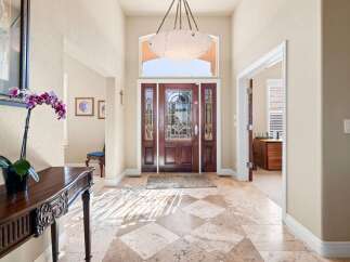 Step into luxury with this stunning entryway! The grand entrance features a beautiful wooden door, elegant marble flooring, and a stylish chandelier.