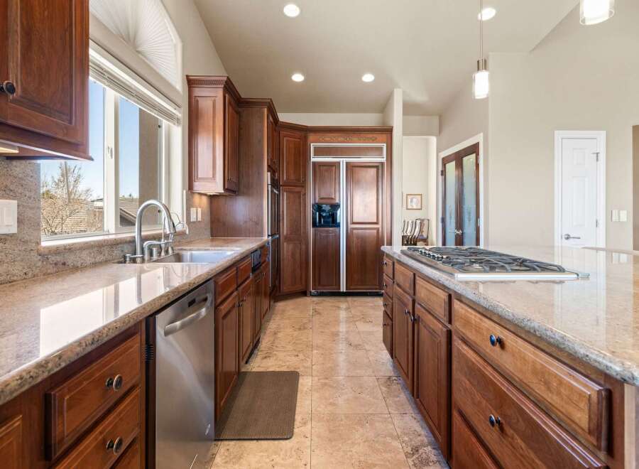 This stunning kitchen boasts rich, wooden cabinetry and elegant granite countertops, creating a warm and inviting atmosphere.