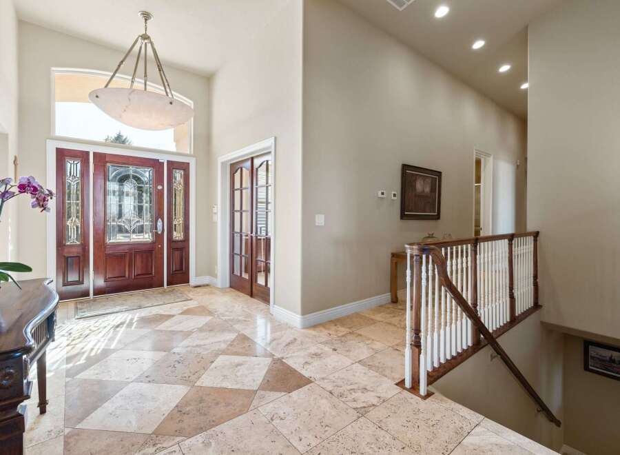 Step into luxury with this stunning entryway! Featuring a grand entrance with a beautiful chandelier, elegant wooden doors, and exquisite flooring.