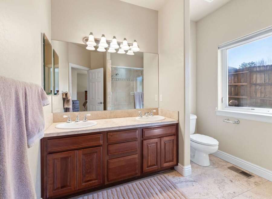 This stunning bathroom features a double vanity with a beautiful countertop and rich, dark wood cabinetry, offering ample storage space.
