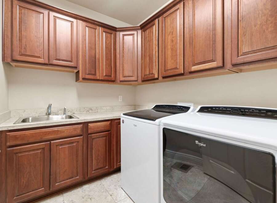 This laundry room features beautiful wooden cabinetry, offering ample storage space for all your laundry essentials.