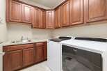 This laundry room features beautiful wooden cabinetry, offering ample storage space for all your laundry essentials.