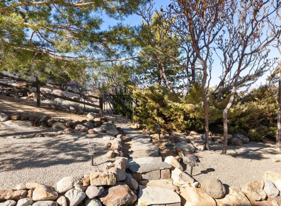 Discover the tranquility of this beautifully landscaped property, featuring a charming stone pathway leading to a gated entrance.