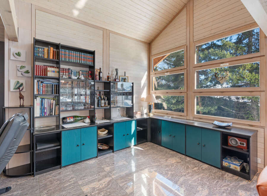 This spacious living area features a stunning floor-to-ceiling bookshelf and bar, perfect for entertaining guests.
