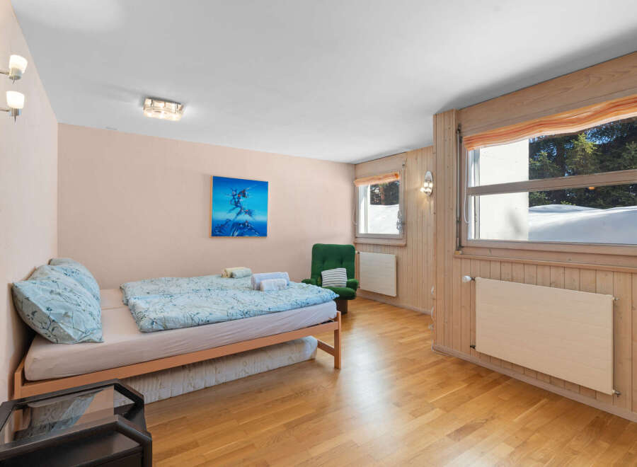 Experience cozy living in this charming room featuring a comfortable bed with light blue patterned bedding and plush pillows.