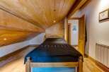 Discover the charm of this cozy bedroom featuring a unique wooden sloped ceiling and exposed beams, creating a warm and inviting atmosphere.