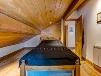 Discover the charm of this cozy bedroom featuring a unique wooden sloped ceiling and exposed beams, creating a warm and inviting atmosphere.