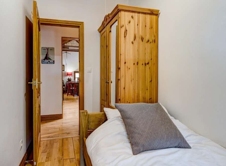 This charming bedroom features a cozy single bed with a stylish striped pillow.