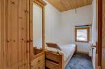This cozy bedroom features a wooden bed frame and a large wardrobe with a mirror, offering ample storage and a touch of rustic charm.