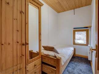 This cozy bedroom features a wooden bed frame and a large wardrobe with a mirror, offering ample storage and a touch of rustic charm.