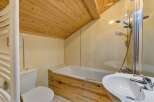 This charming bathroom features a unique wooden ceiling and a stylish wooden accent on the bathtub.