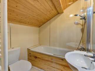 This charming bathroom features a unique wooden ceiling and a stylish wooden accent on the bathtub.