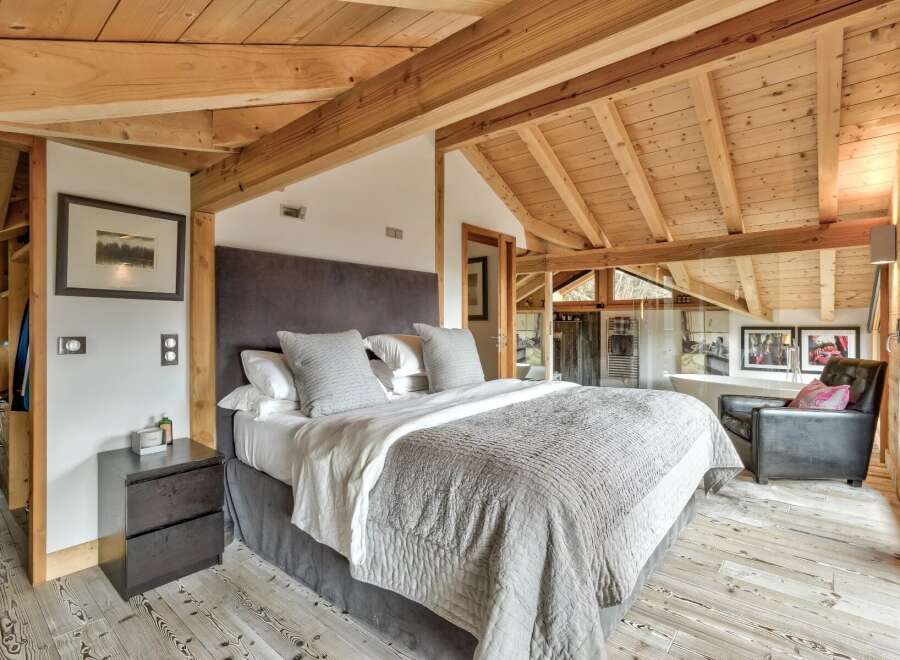 Experience luxury in this stunning bedroom featuring a cozy bed and a stylish armchair.