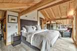 Experience luxury in this stunning bedroom featuring a cozy bed and a stylish armchair.