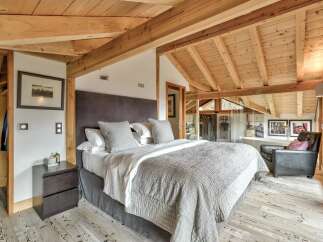 Experience luxury in this stunning bedroom featuring a cozy bed and a stylish armchair.