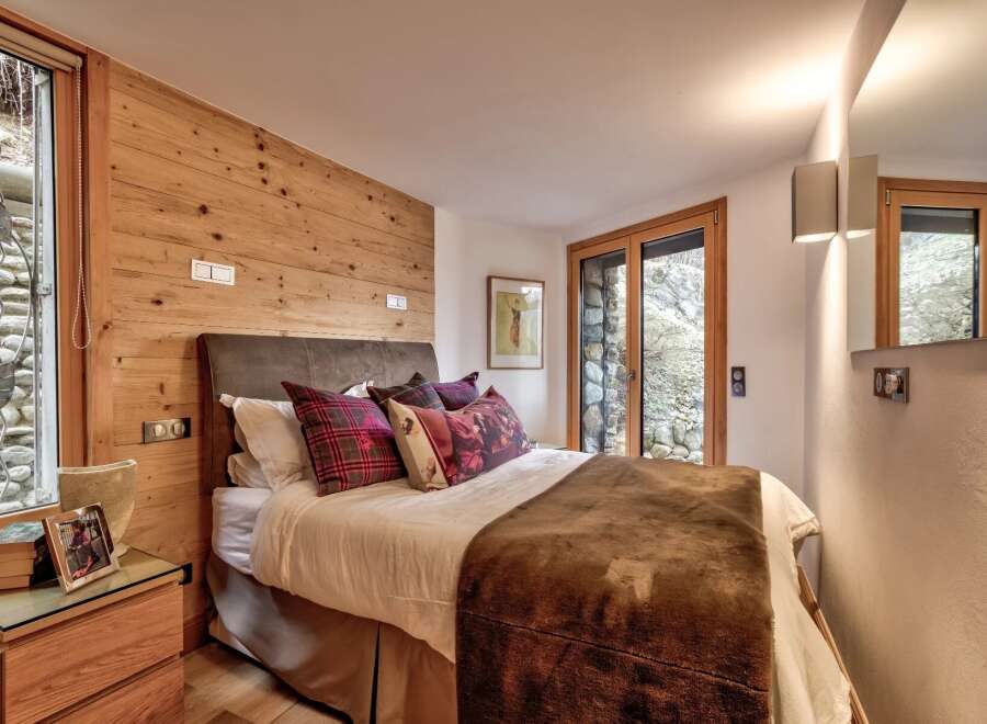 This cozy bedroom features a rustic wooden accent wall and a comfortable bed with plush pillows.