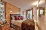 This cozy bedroom features a rustic wooden accent wall and a comfortable bed with plush pillows.