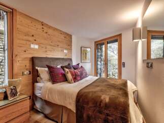 This cozy bedroom features a rustic wooden accent wall and a comfortable bed with plush pillows.