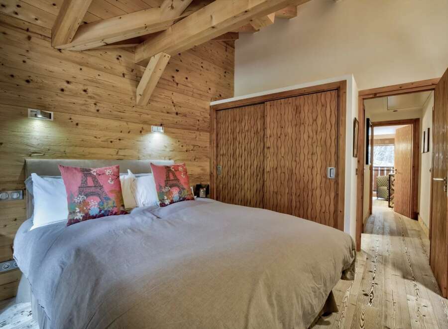 This stunning bedroom showcases rustic charm with its wooden walls and ceiling beams, creating a warm and inviting atmosphere.