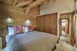 This stunning bedroom showcases rustic charm with its wooden walls and ceiling beams, creating a warm and inviting atmosphere.