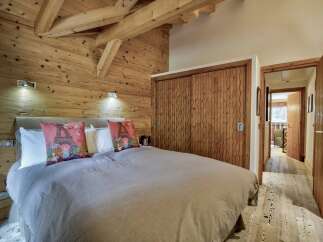 This stunning bedroom showcases rustic charm with its wooden walls and ceiling beams, creating a warm and inviting atmosphere.