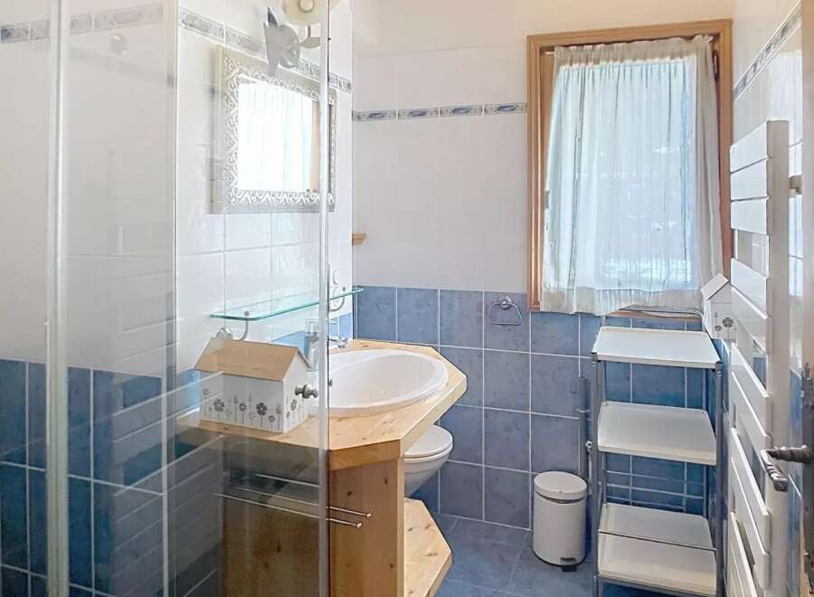Discover this charming bathroom featuring a unique wooden vanity and a stylish shower enclosure.