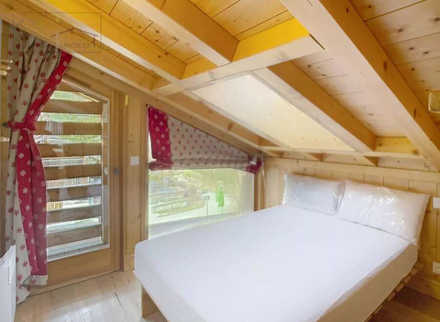 Discover the charm of this cozy bedroom, featuring a unique sloped ceiling and wooden accents that create a warm and inviting atmosphere.