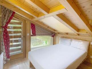 Discover the charm of this cozy bedroom, featuring a unique sloped ceiling and wooden accents that create a warm and inviting atmosphere.