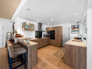 This stunning kitchen boasts modern design with sleek wooden cabinetry and countertops, creating a warm and inviting atmosphere.