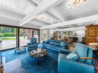 Experience luxury living in this stunning property, featuring a spacious living room with a plush blue carpet and comfortable seating.