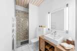 This modern bathroom features a sleek design with a wooden vanity and a stylish sink.